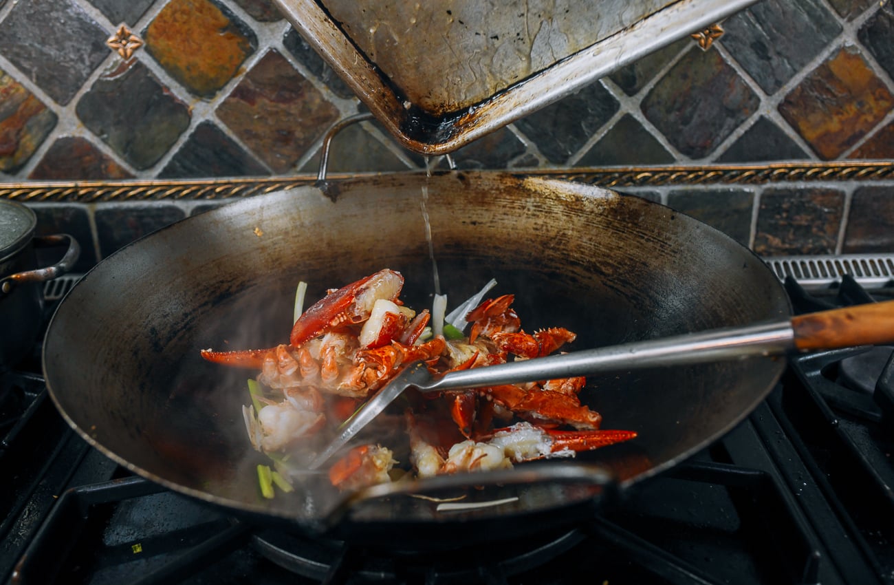 adding lobster to wok with scallions and ginger