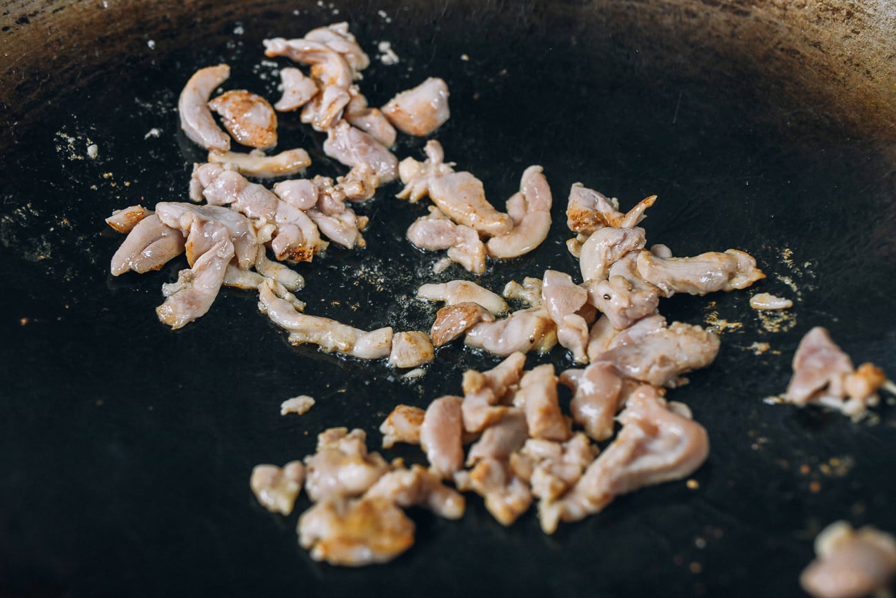 stir-frying sliced chicken in wok
