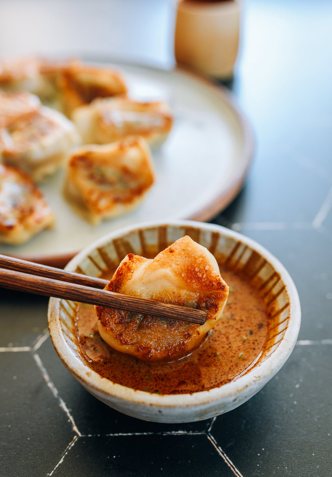 Dipping pan-fried wonton into sesame sauce