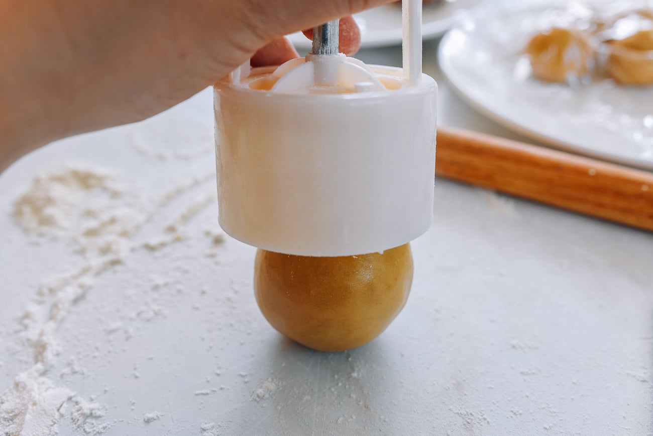 putting mooncake mold over ball of dough and filling