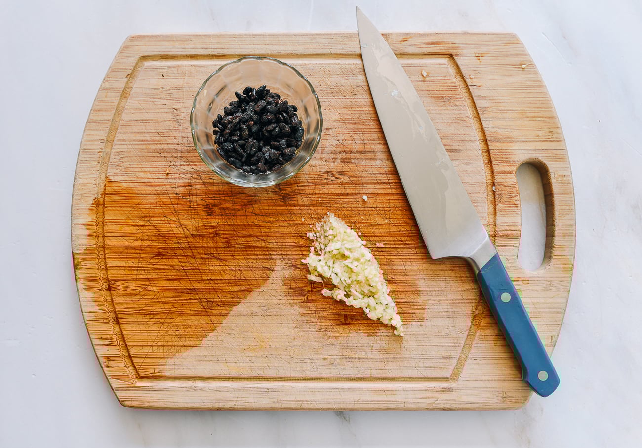 black beans in bowl and chopped garlic on cutting board