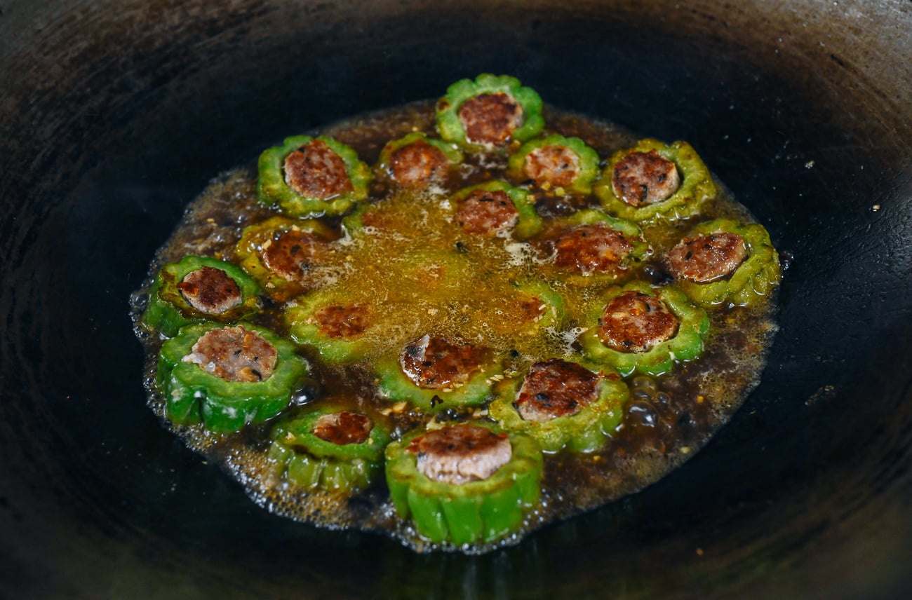 Pan-fried stuffed bitter melon pieces simmering in wok