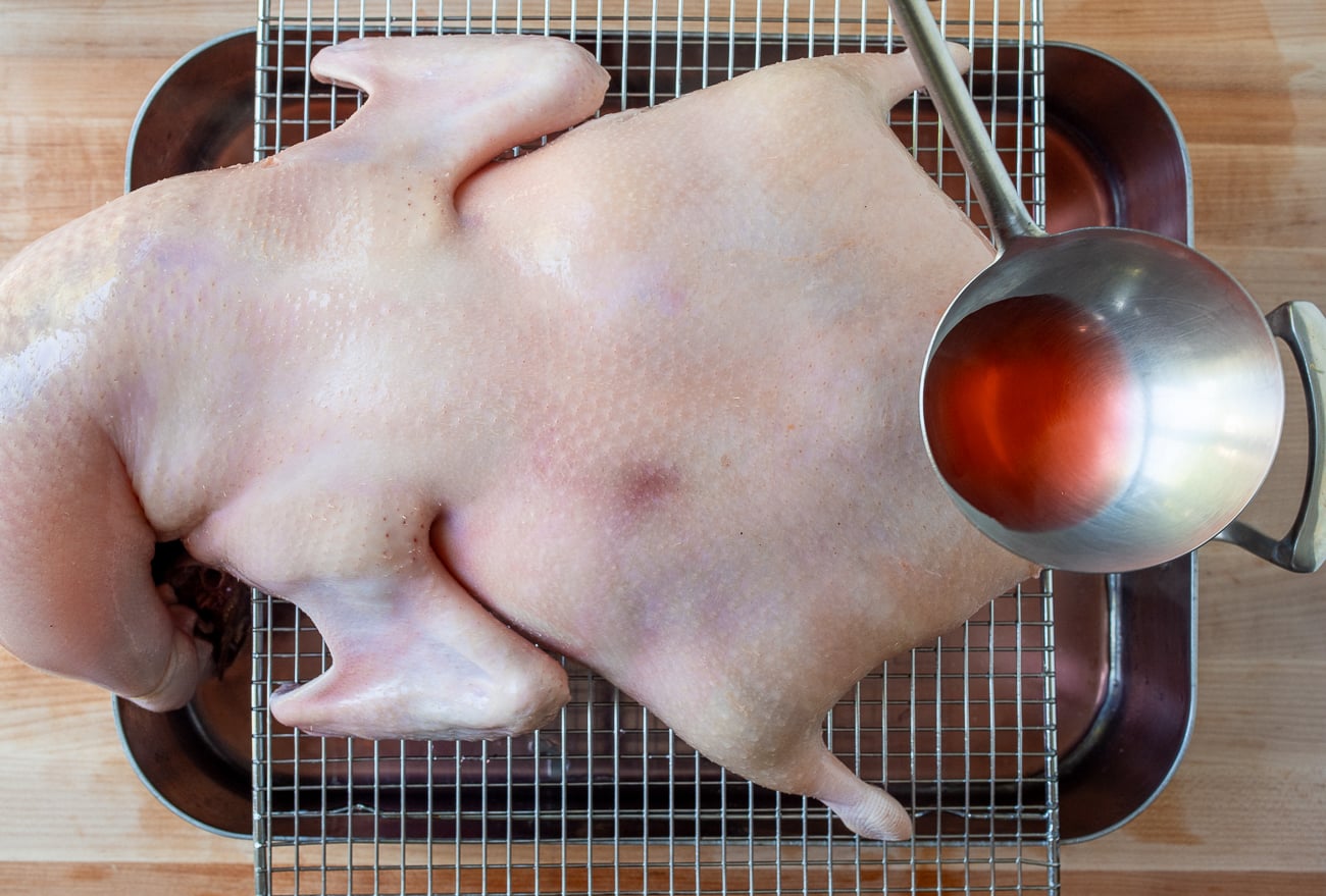 Pouring hot Chinese red vinegar solution over duck
