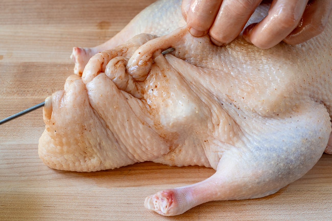 weaving metal skewer through duck skin to seal cavity