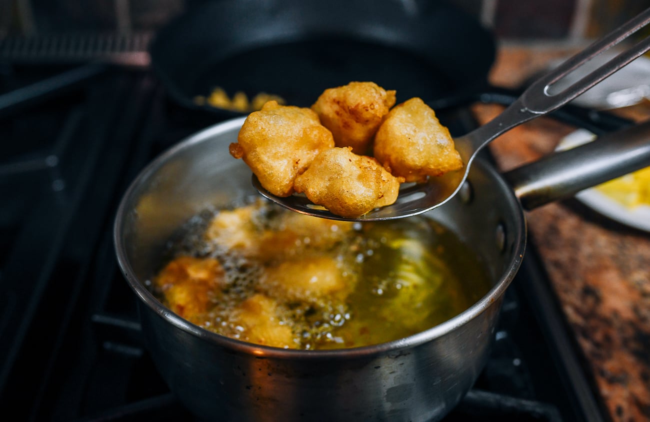removing fried chicken pieces from pot using slotted spoon