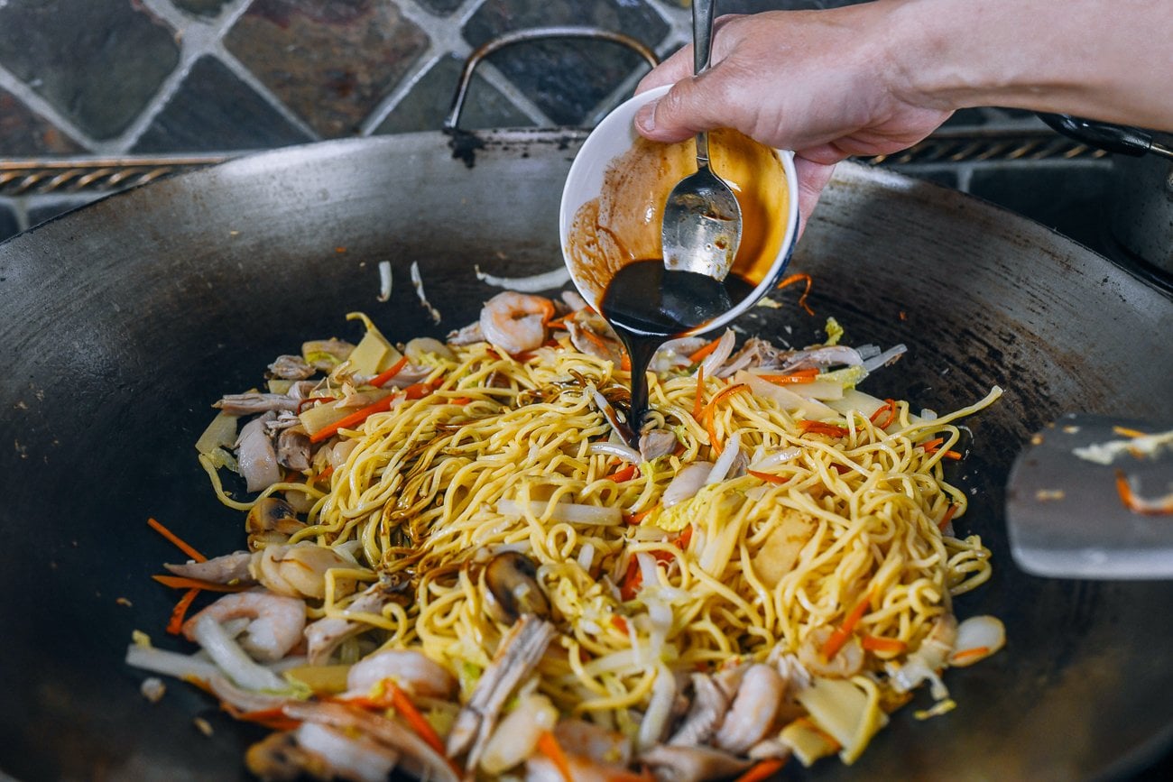 pouring lo mein sauce over noodles