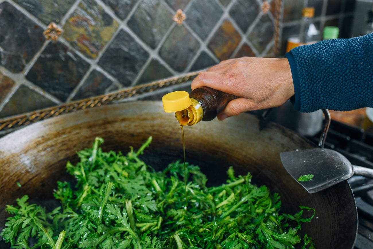 adding sesame oil to tong ho in wok