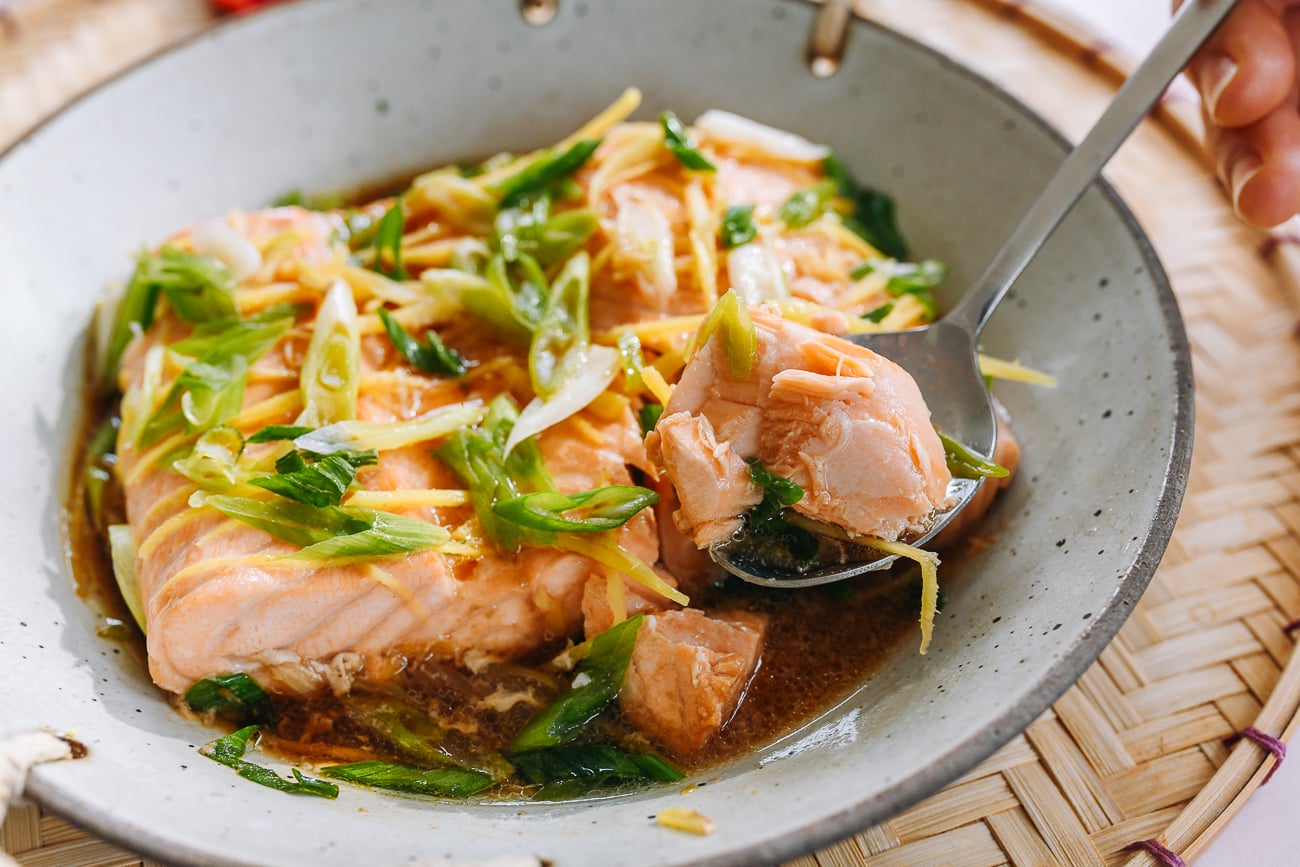 flaking off piece of steamed salmon from fillet