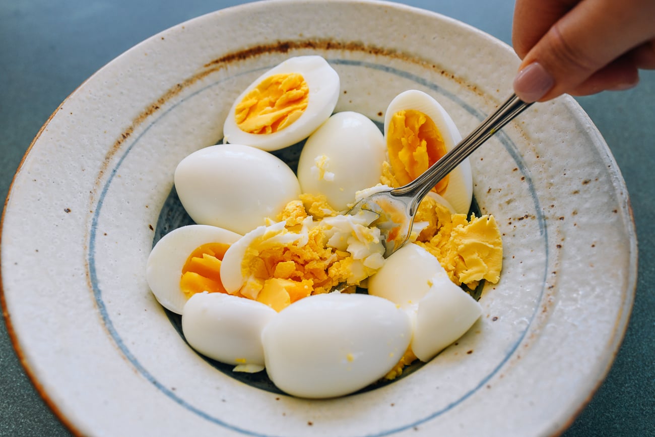 mashing hard boiled eggs in a bowl with a fork