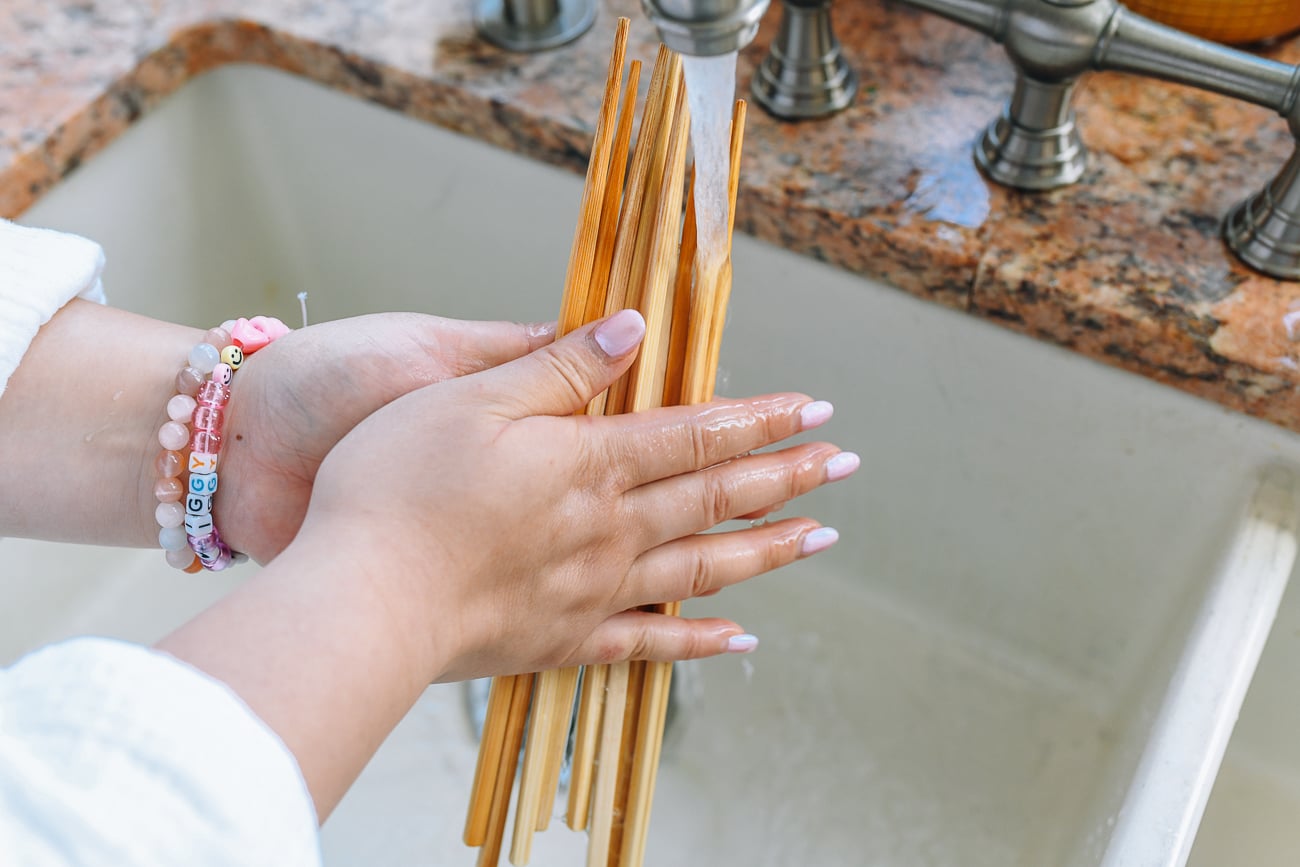 rolling chopsticks between hands under running water
