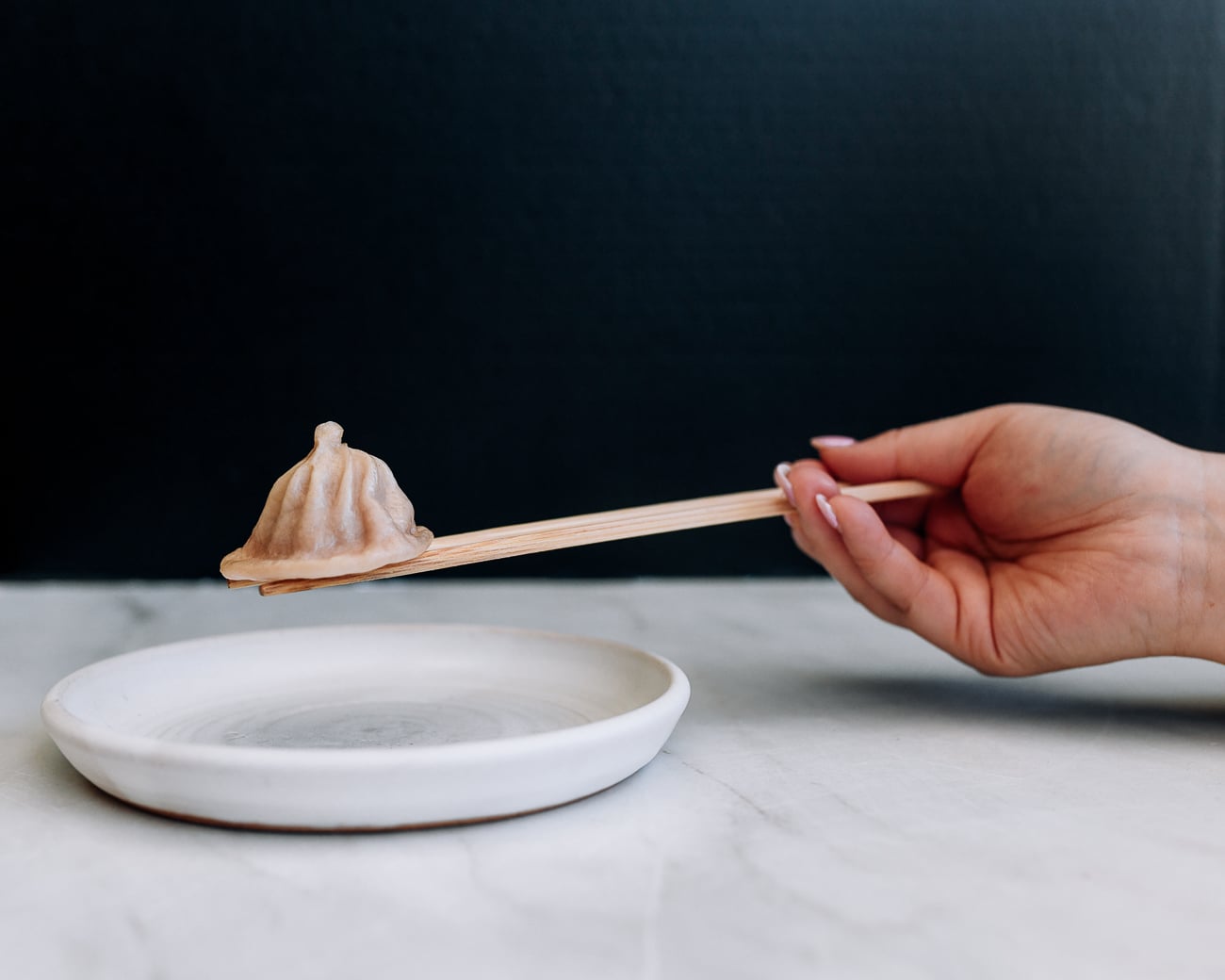 resting dumpling on top of pair of chopsticks