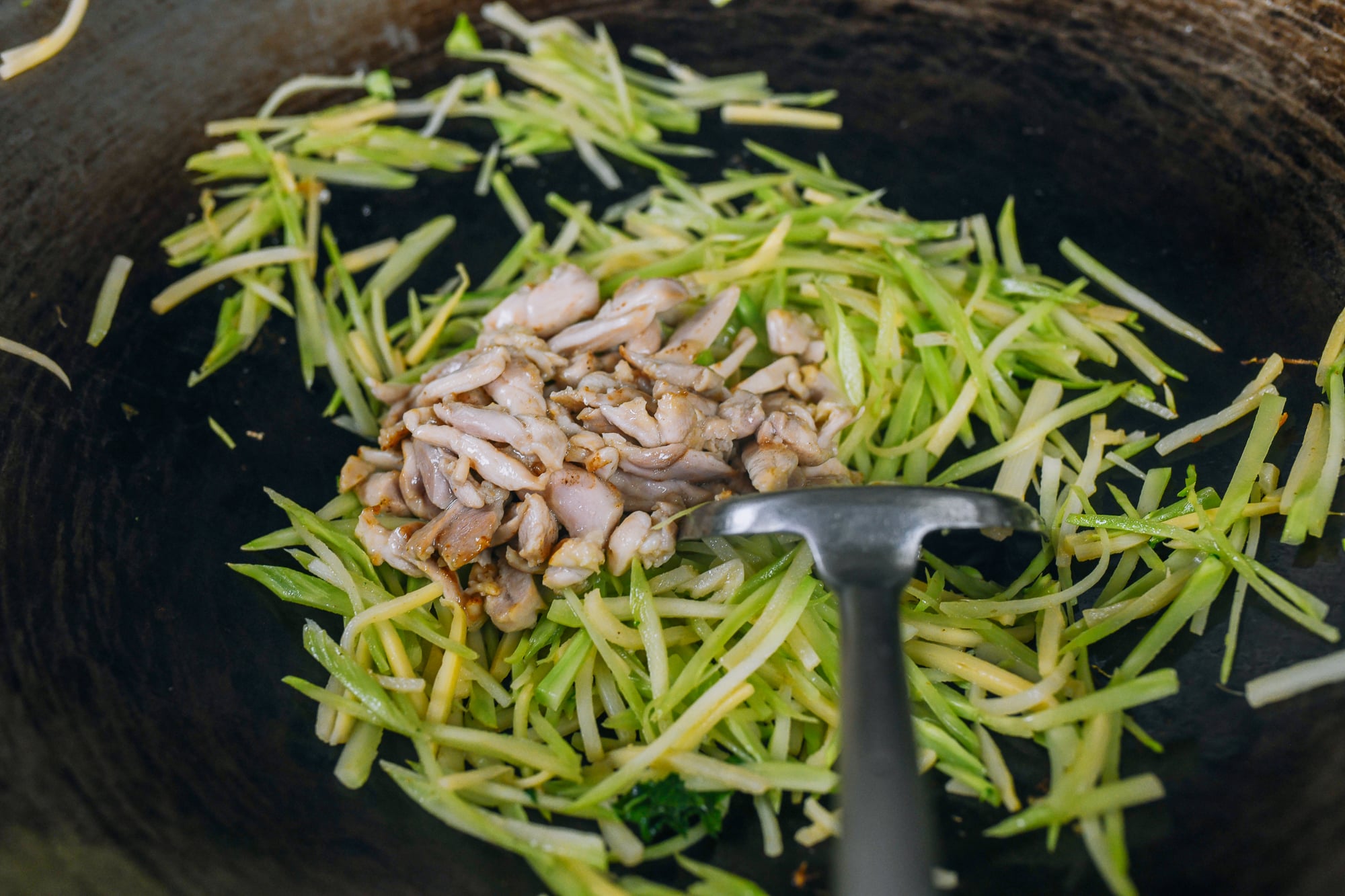 chicken added to wok with julienned vegetables