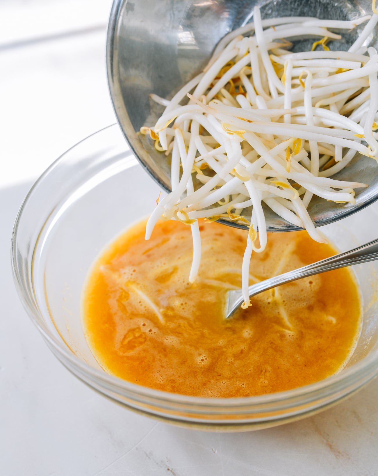 adding bean sprouts to beaten eggs