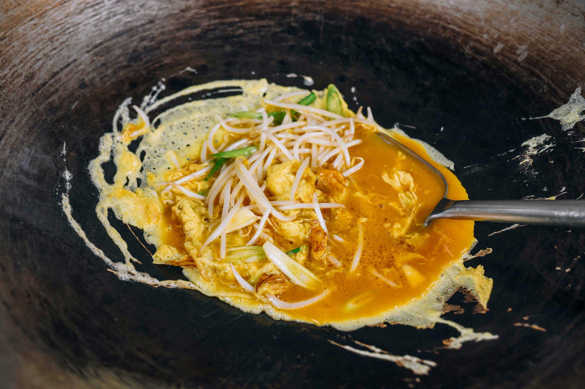 scrambling eggs in wok with bean sprouts and scallions