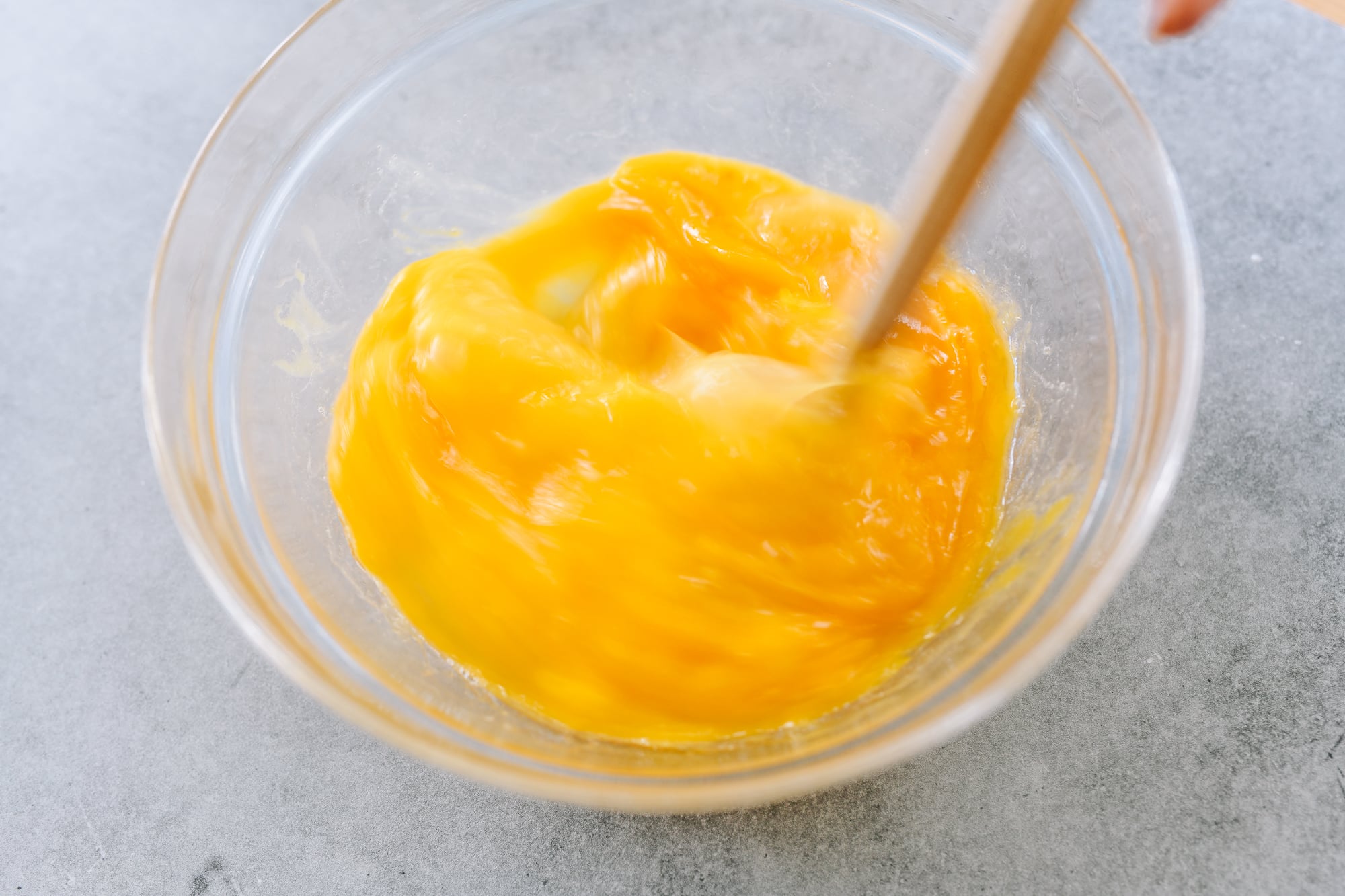 beating eggs in glass bowl