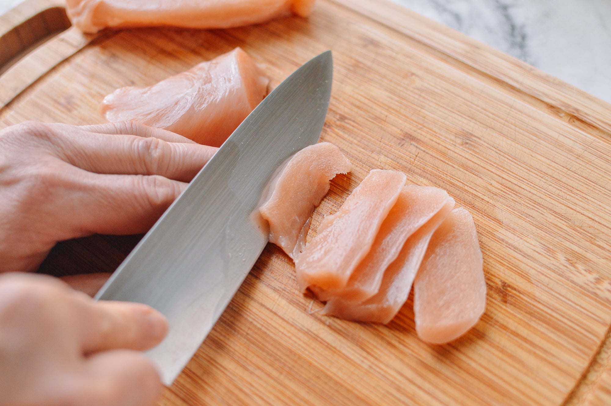 cutting boneless skinless chicken breast into slices for stir-fry