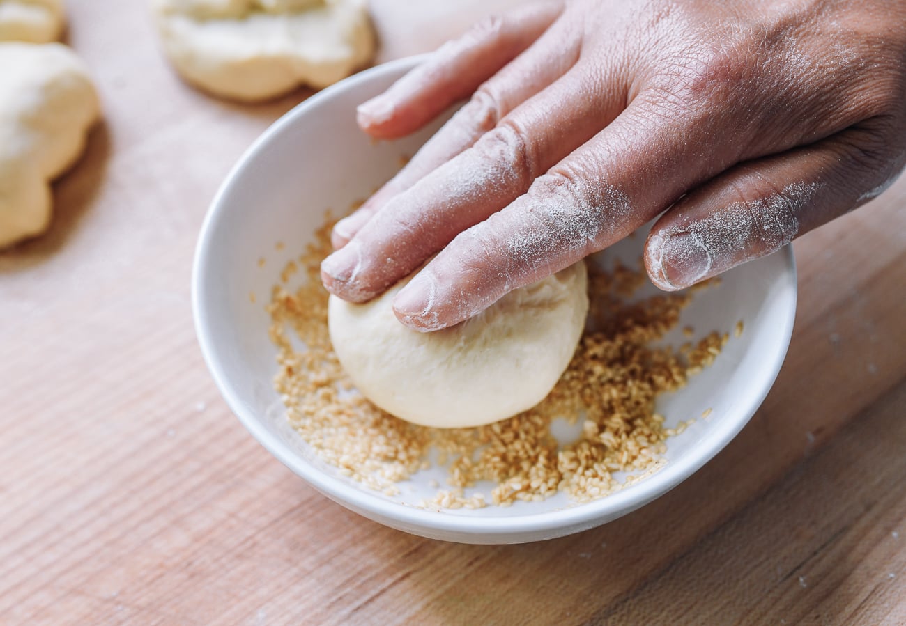 rolling dough ball in damp sesame seeds