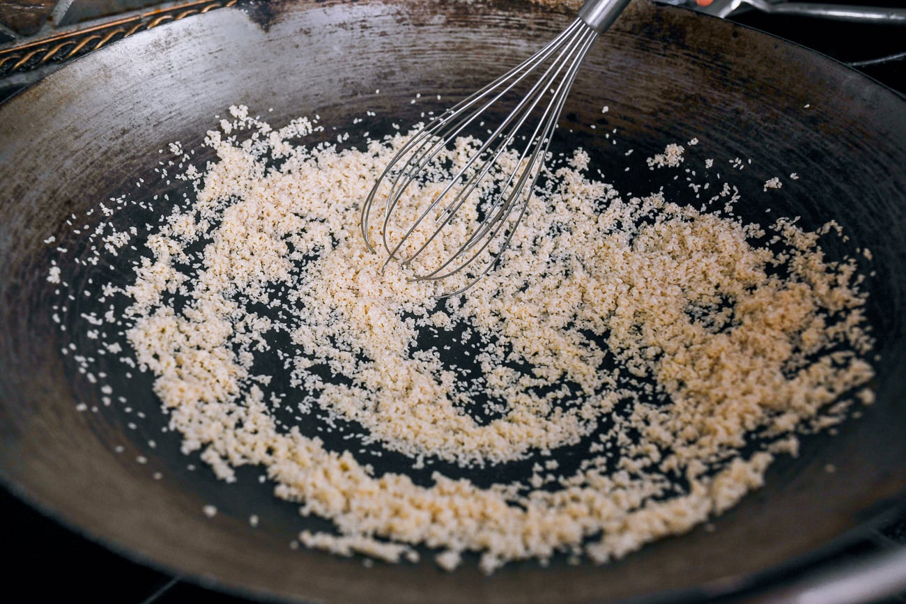stirring sesame seeds in wok