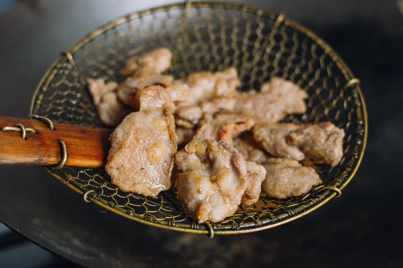 scooping fried chicken pieces in spider strainer