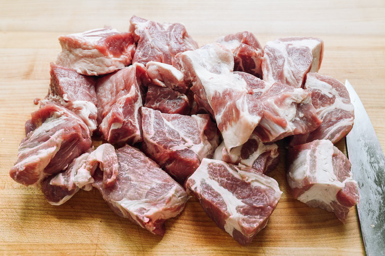pork butt cut into large pieces on cutting board