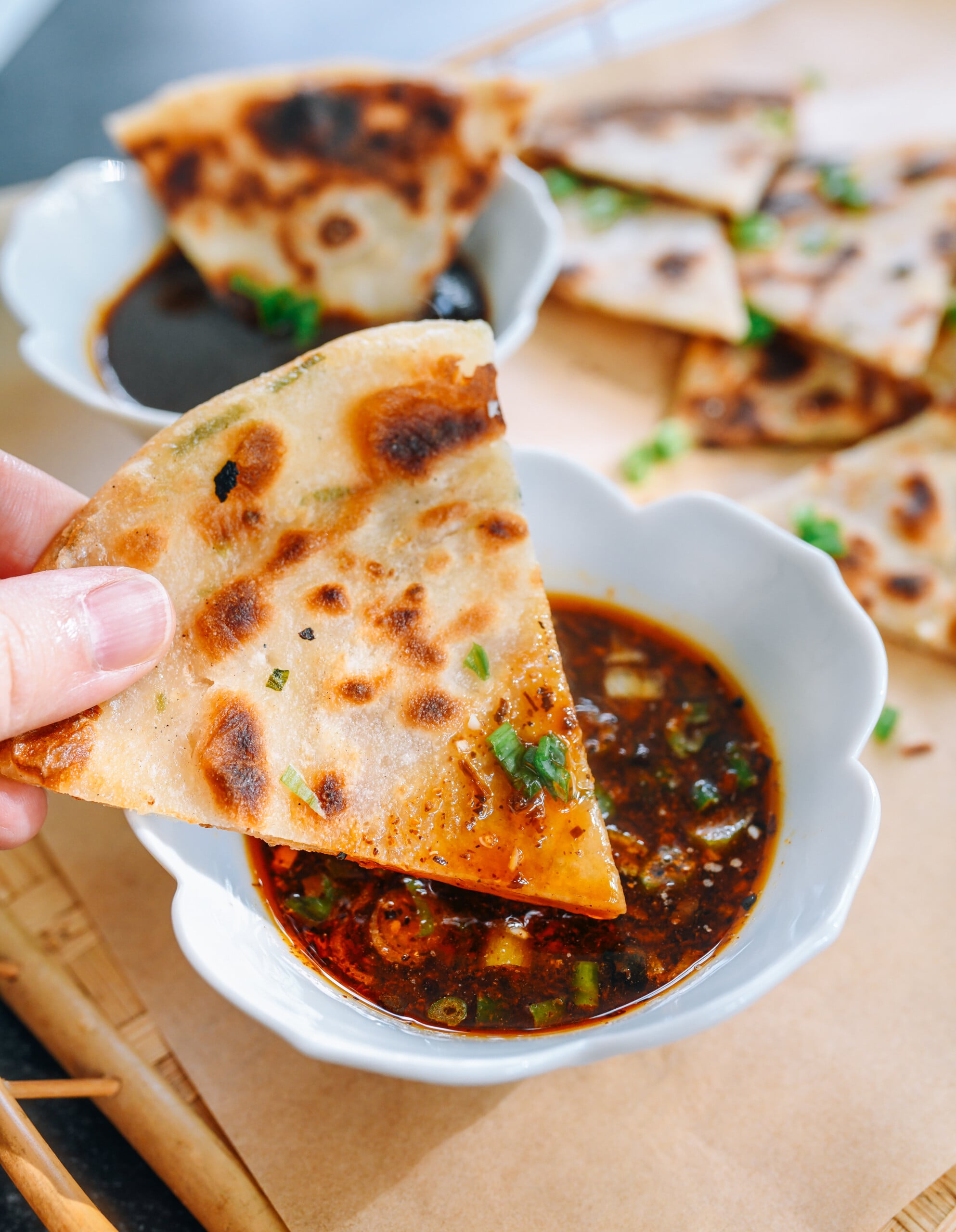 dipping scallion pancake into sauce