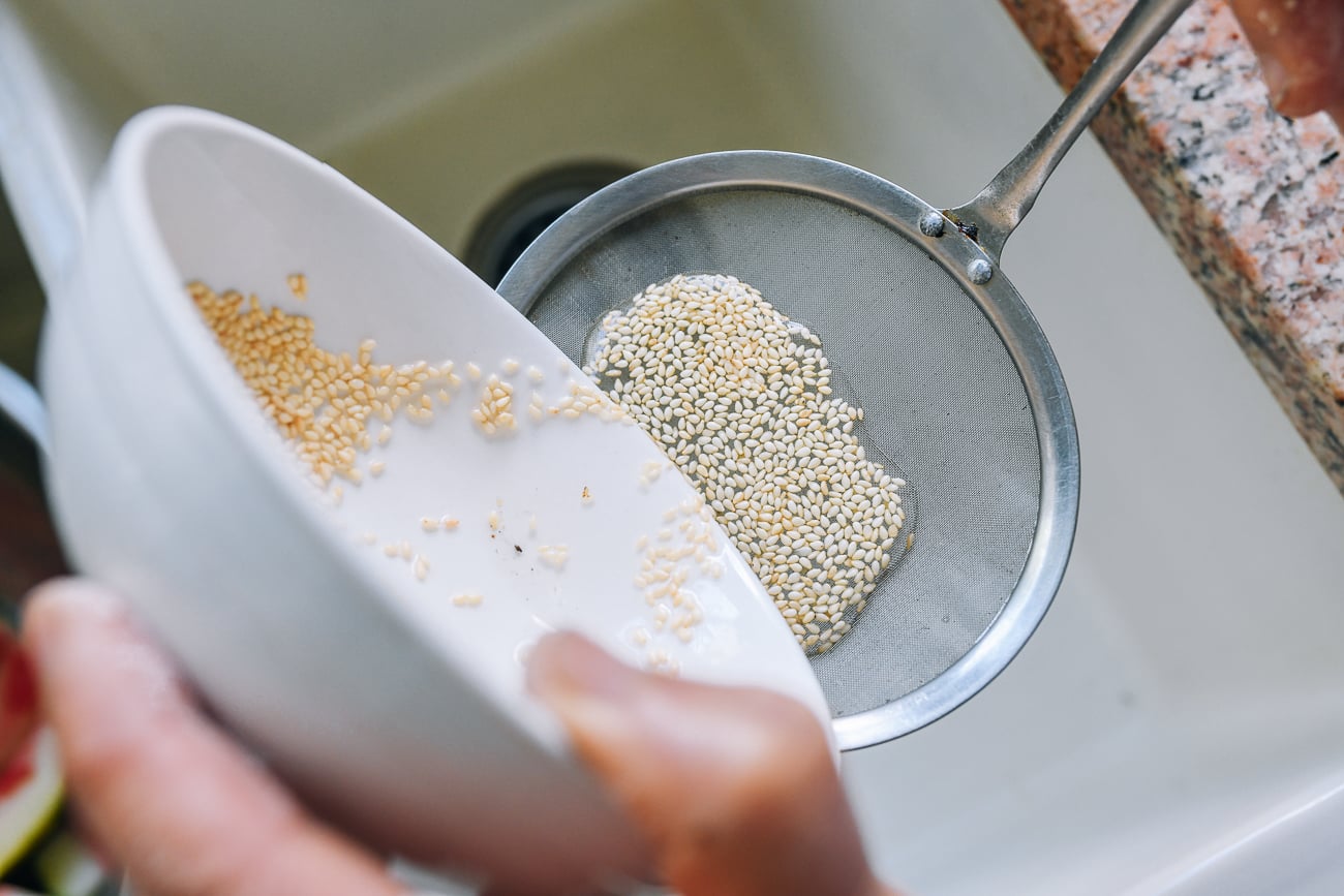 using a fine meshed strainer to strain soaked sesame seeds