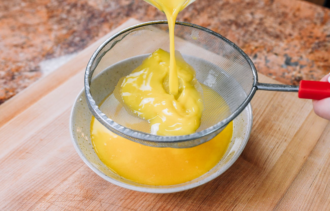 pouring egg mixture through a fine mesh strainer