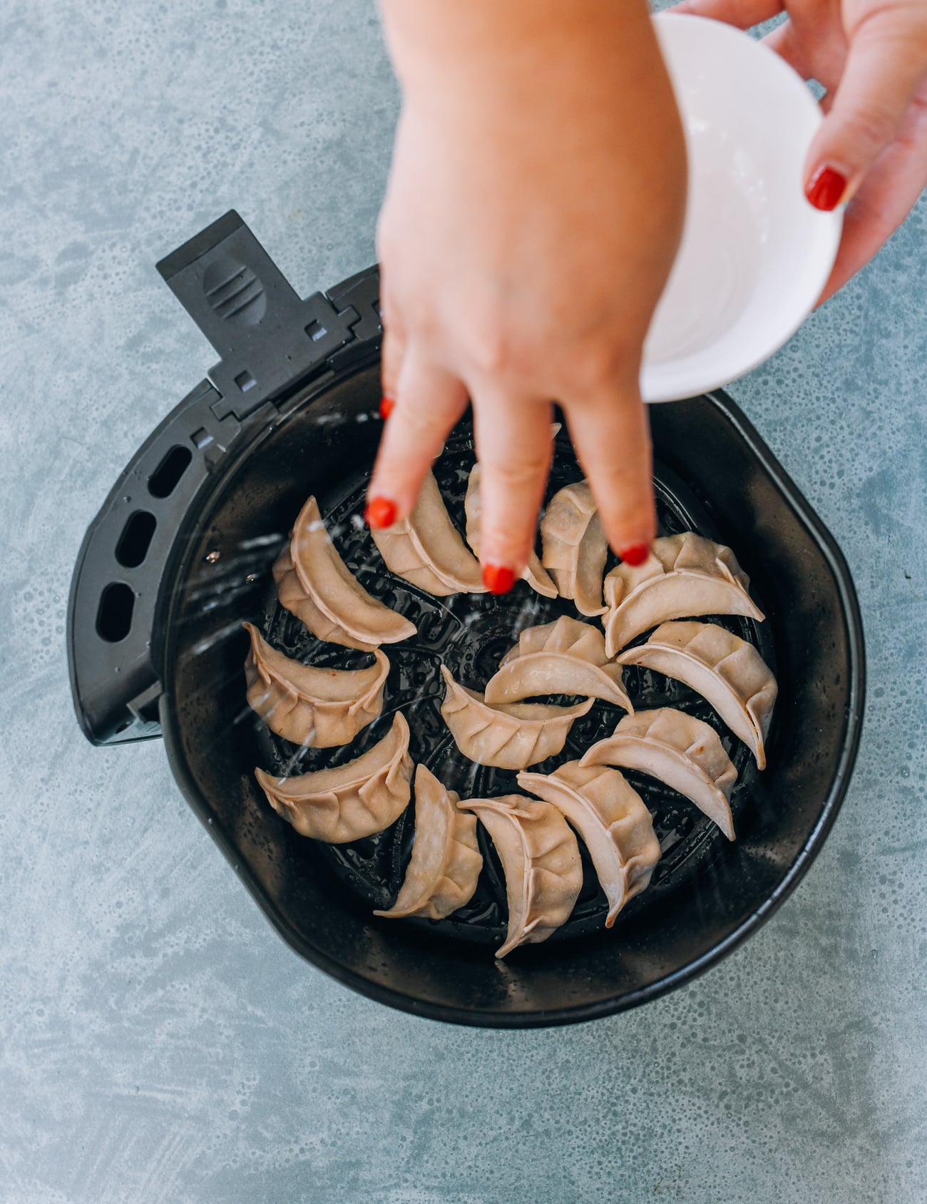 using fingers to flick water onto dumplings in air fryer