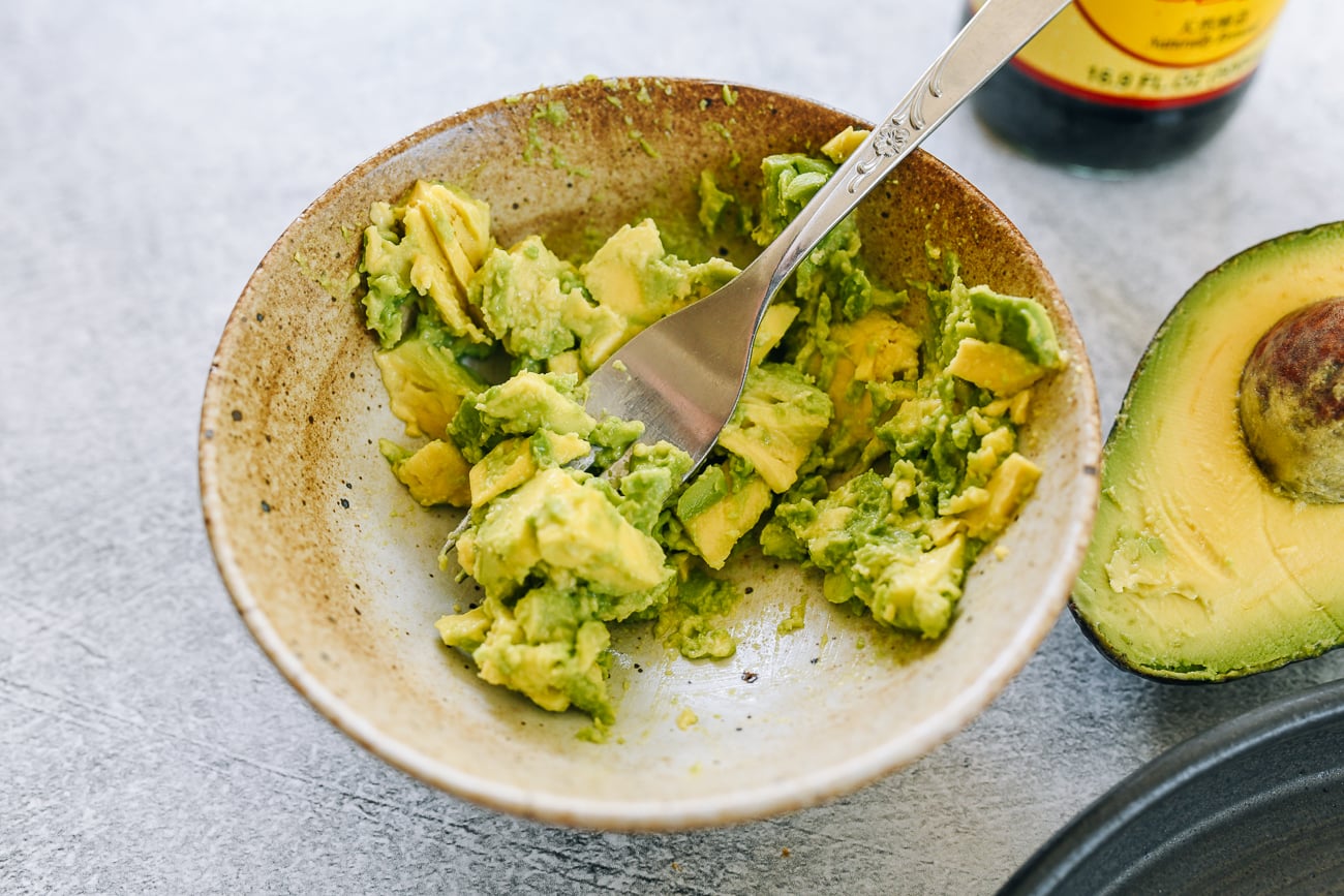mashing avocado in bowl