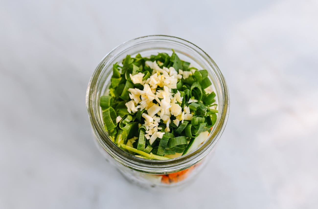 vegetables and chopped herbs at the top of mason jar