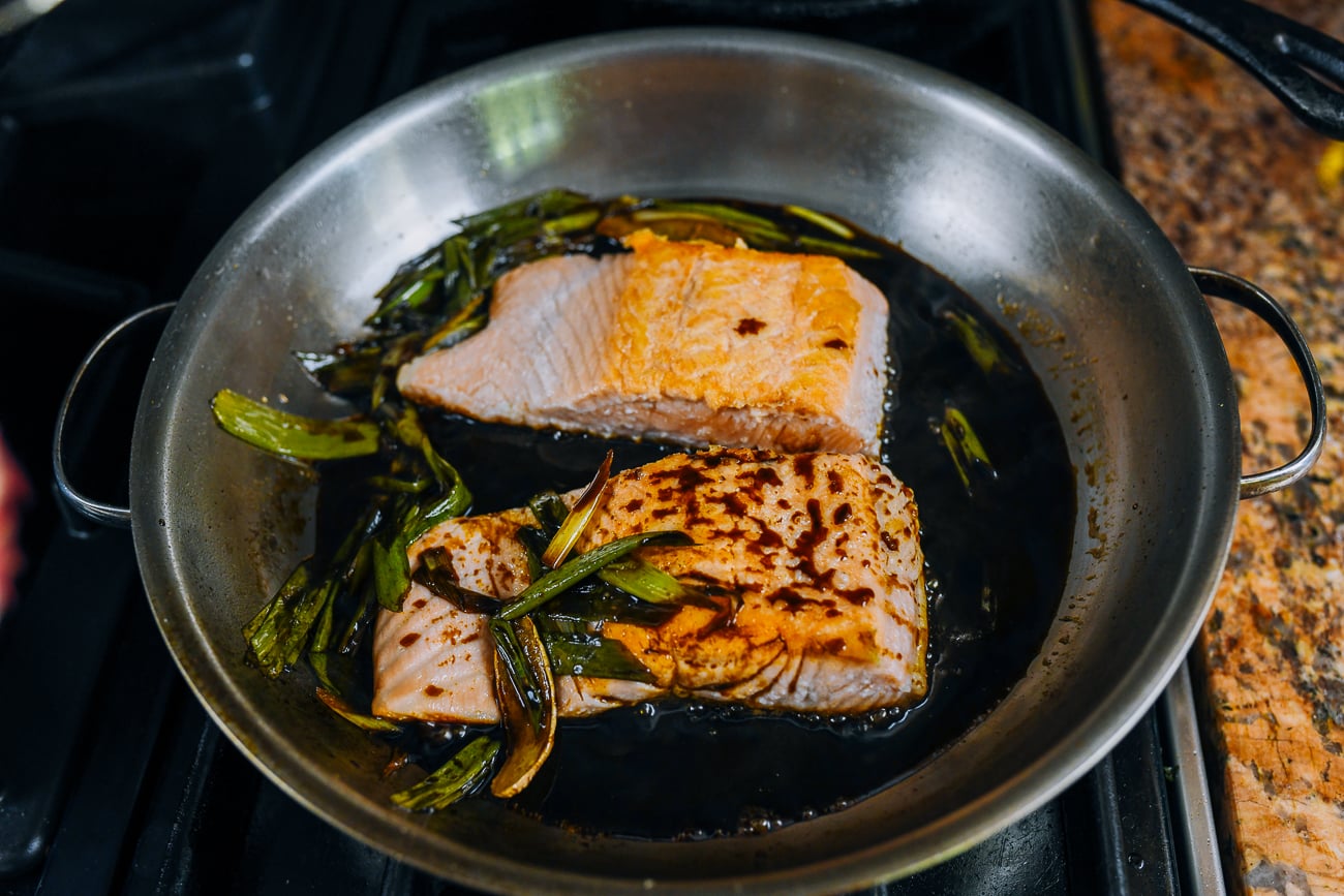 spooning sauce over salmon fillets