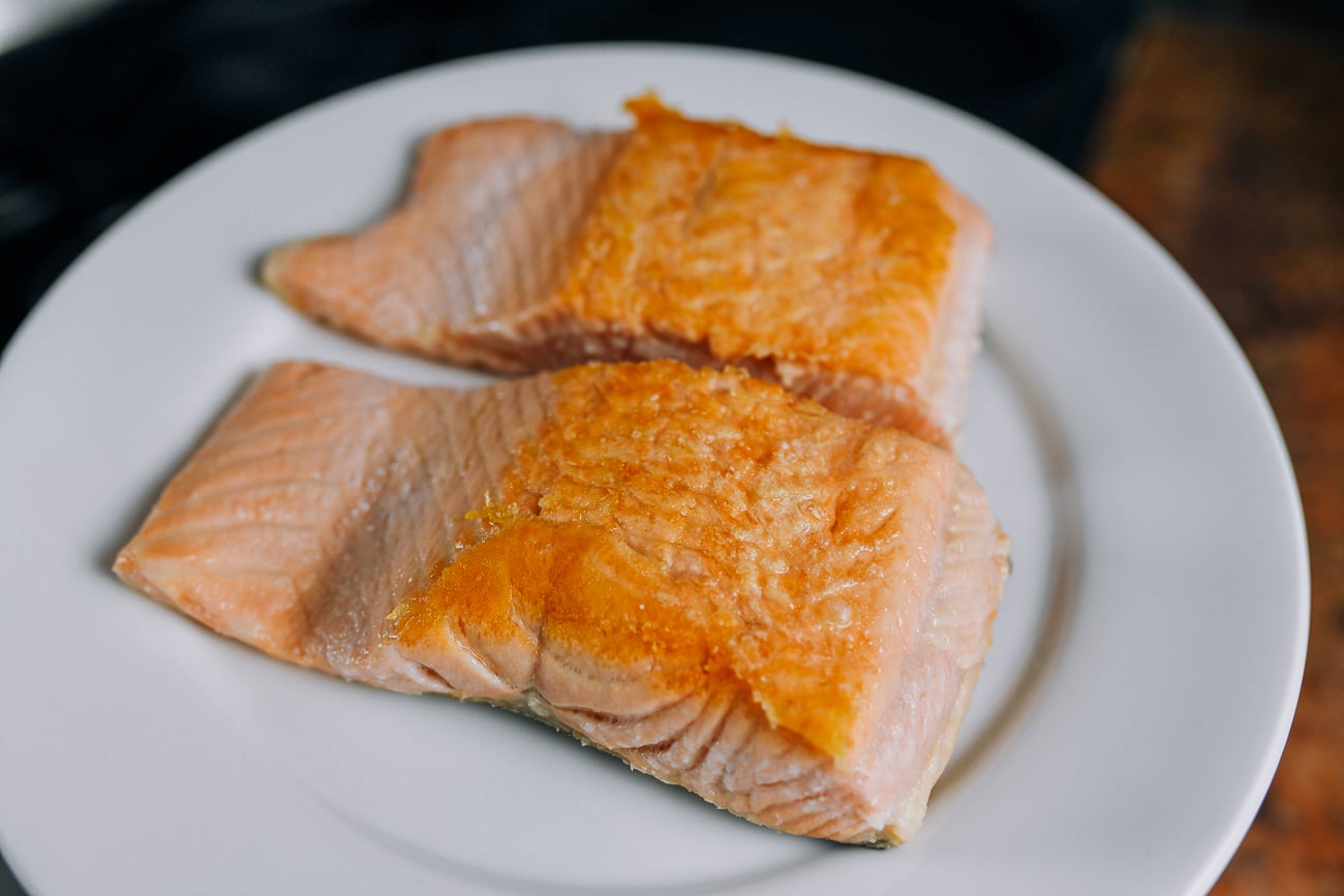 two seared salmon fillets on white plate