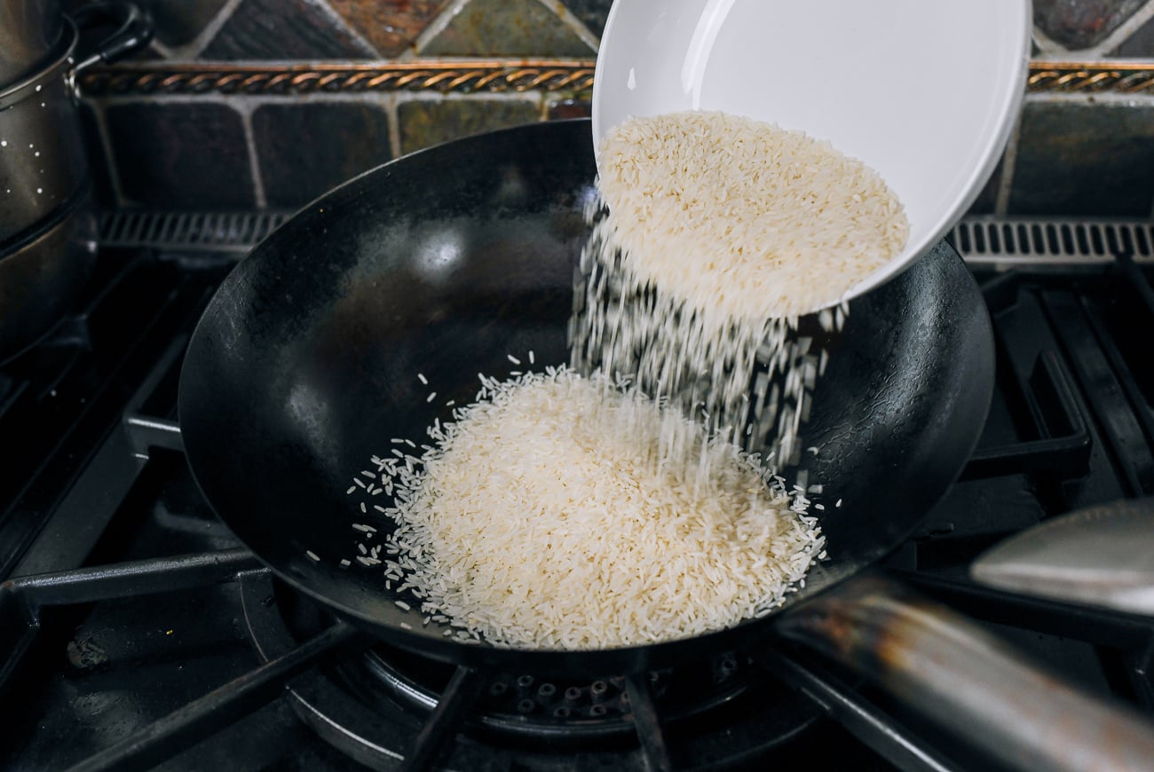 adding rice to wok with chicken fat and garlic