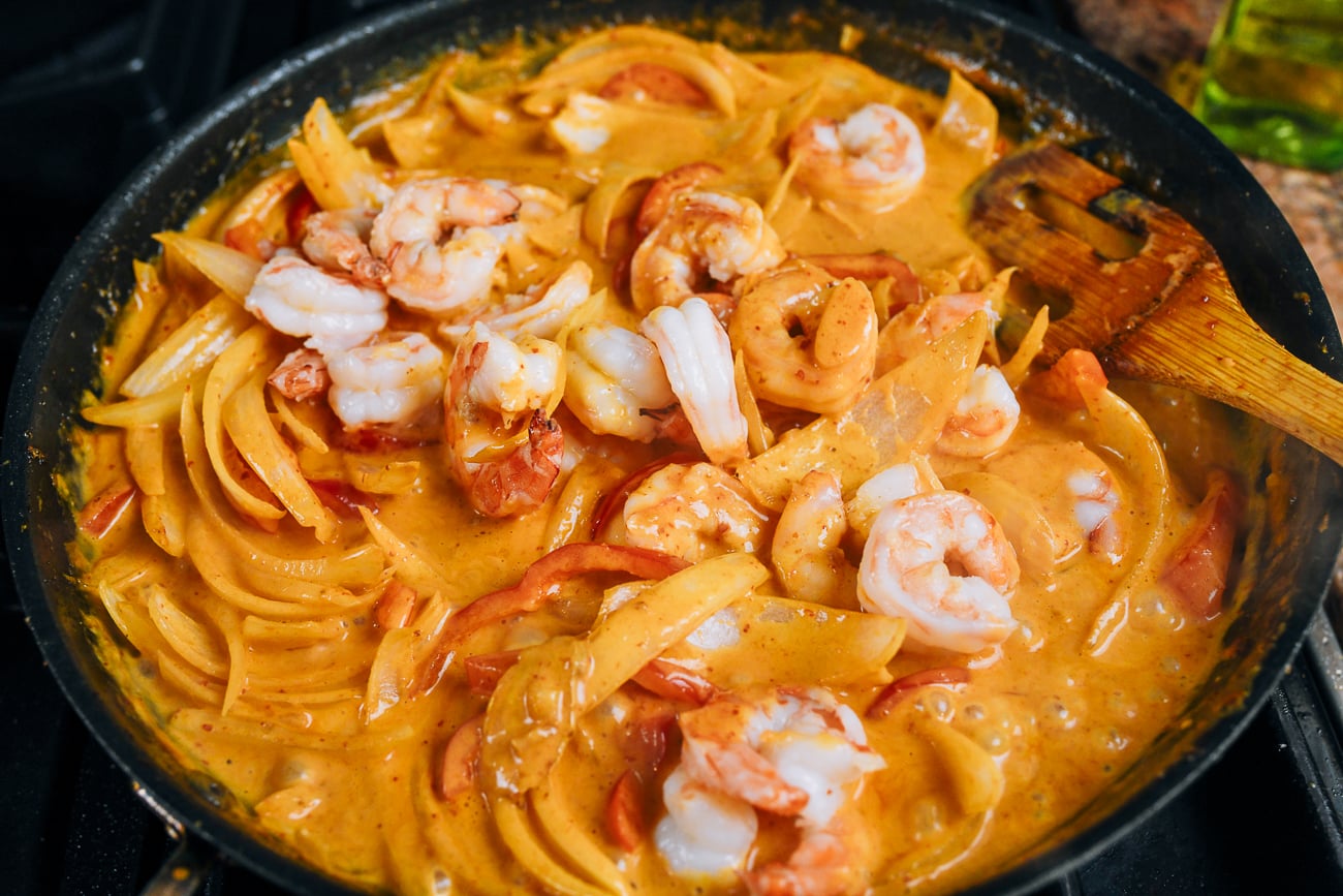 adding shrimp to red curry sauce