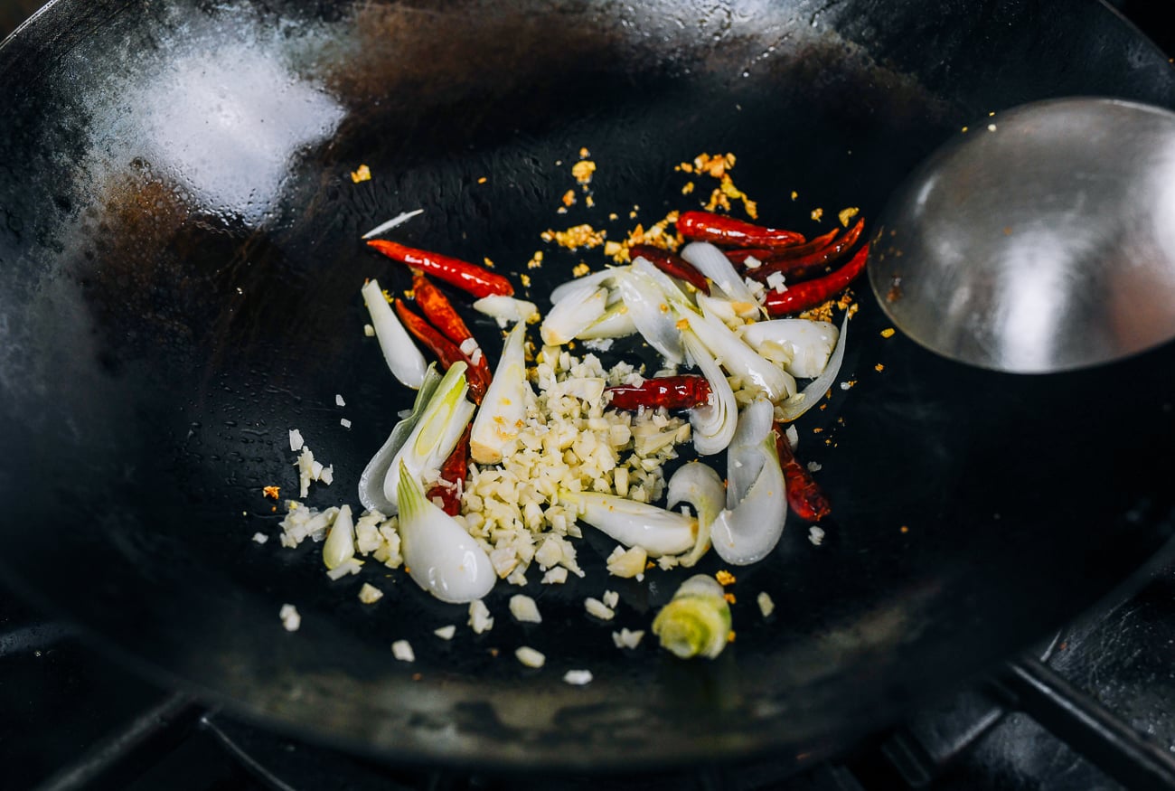 ginger, chilies, garlic, and white portions of scallions in wok