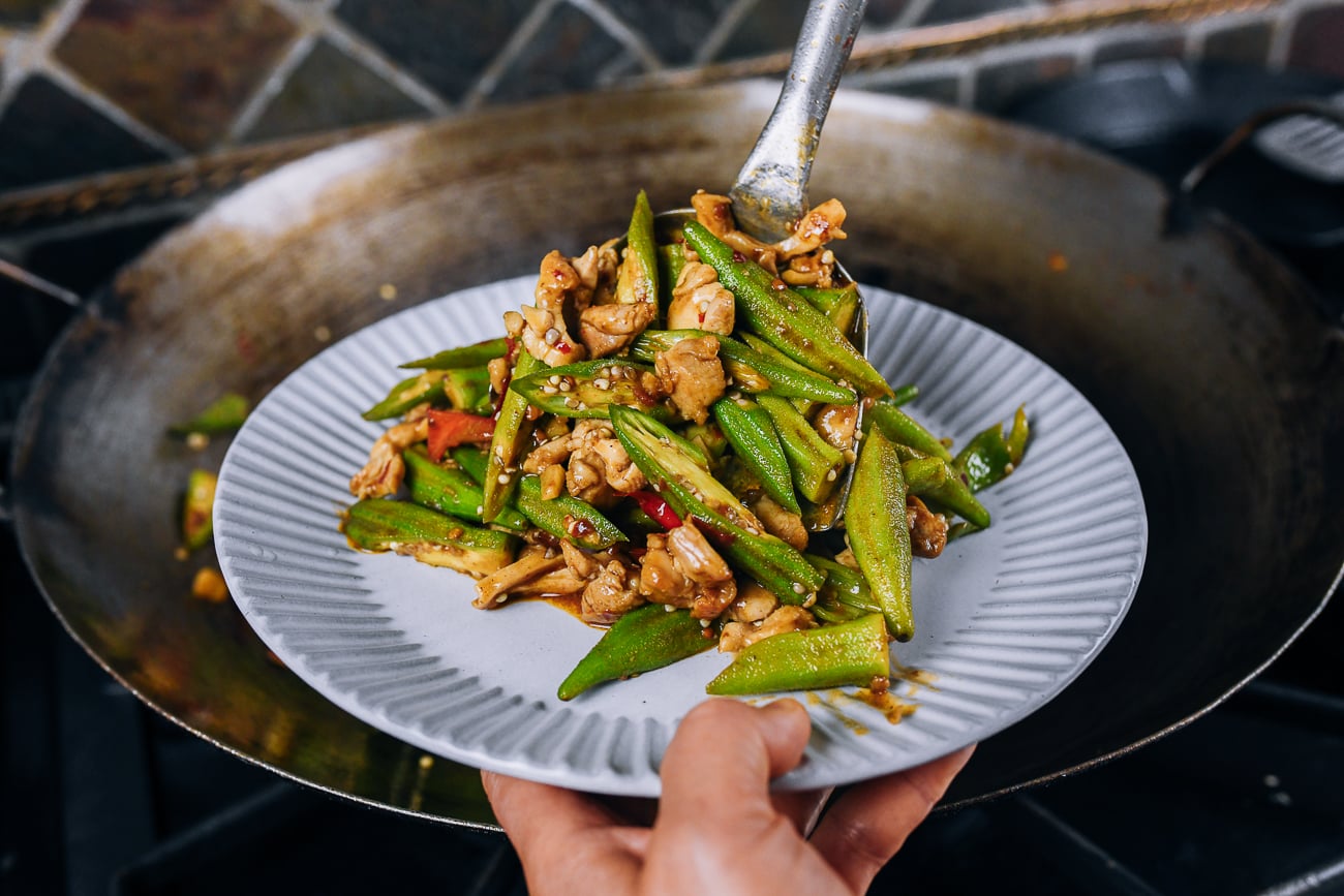 Dishing up okra stir-fry with chicken onto plate