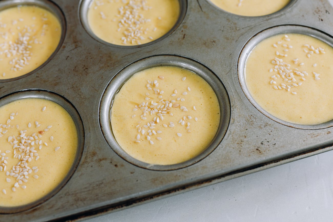 cake batter in muffin tins topped with sesame seeds