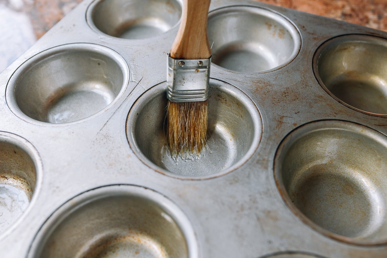 brushing muffin tins with oil