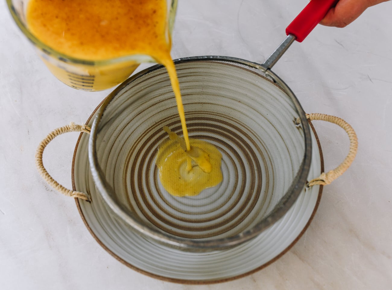 pouring egg mixture through fine meshed strainer into dish