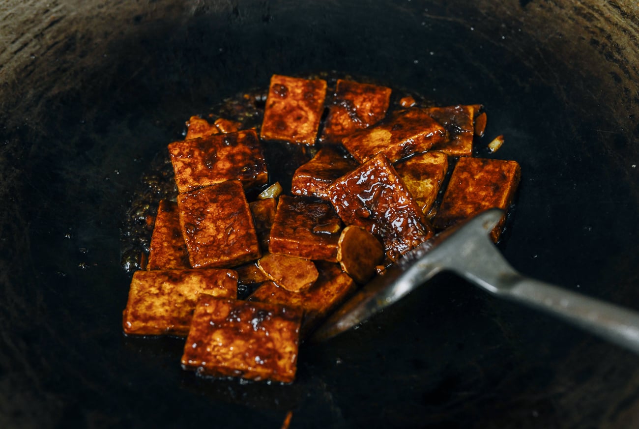 mixing tofu pieces in three cup sauce