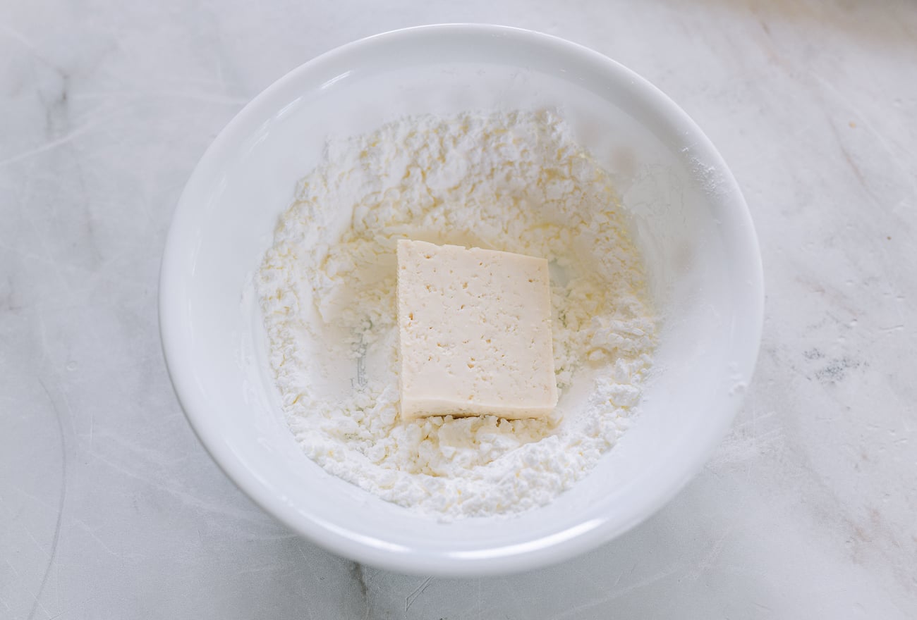 piece of tofu in bowl of cornstarch