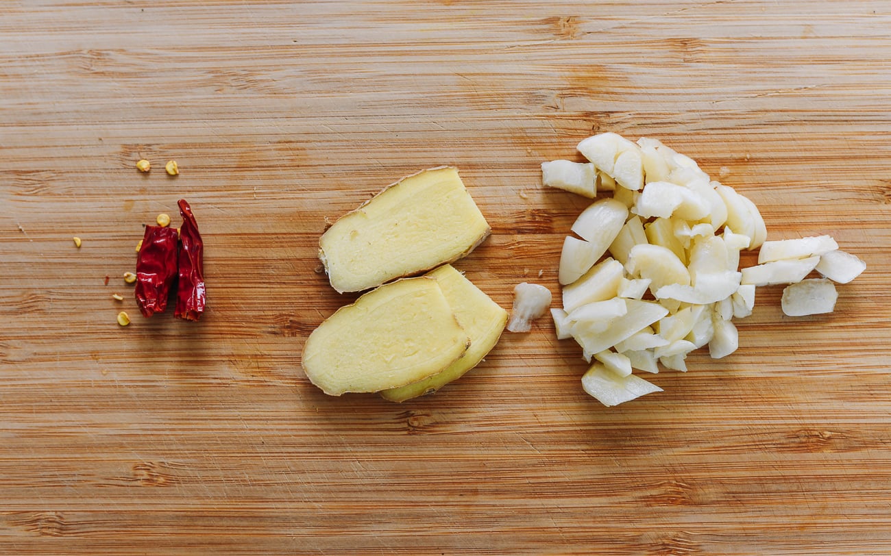 dried red chili, ginger slices, and chopped garlic on cutting board