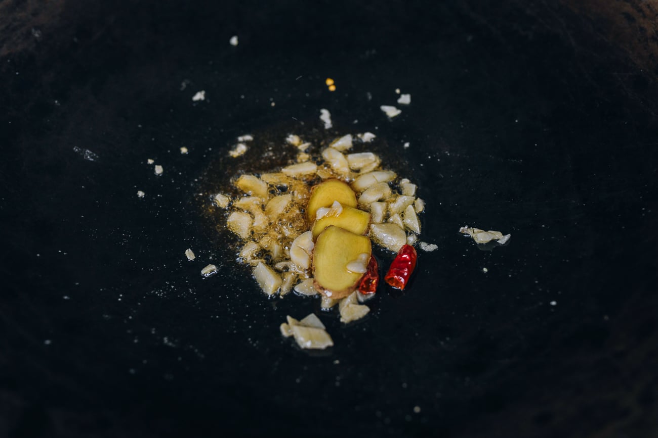 cooking garlic, ginger, and chili in oil in wok