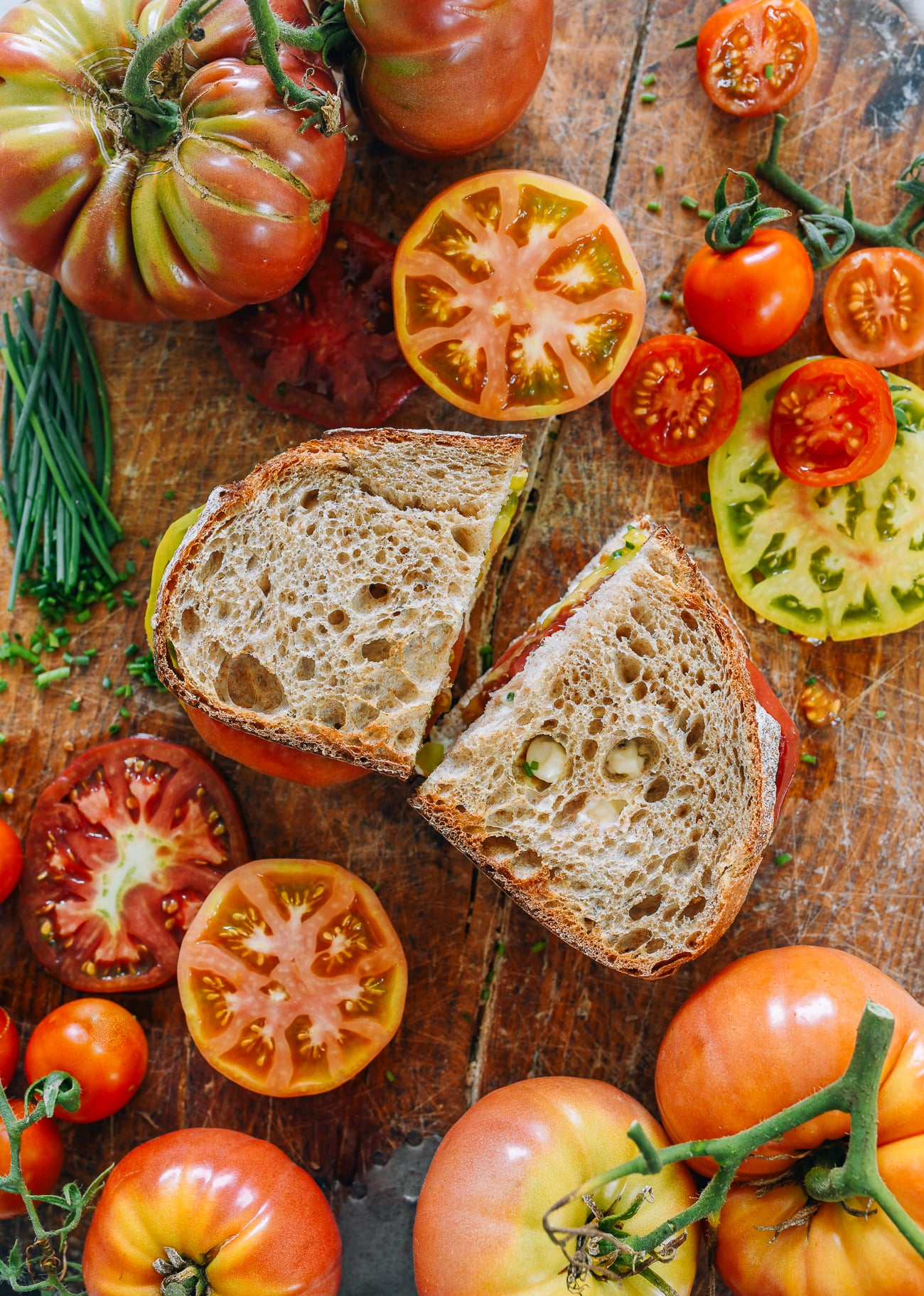 Tomato sandwich on cutting board with heirloom tomatoes