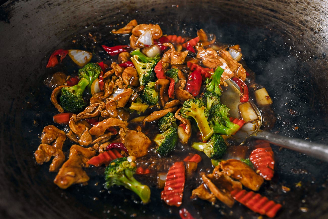 stir-frying chicken with mixed vegetables in wok