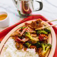 Picking up piece of Chinese takeout chicken with mixed vegetables with chopsticks