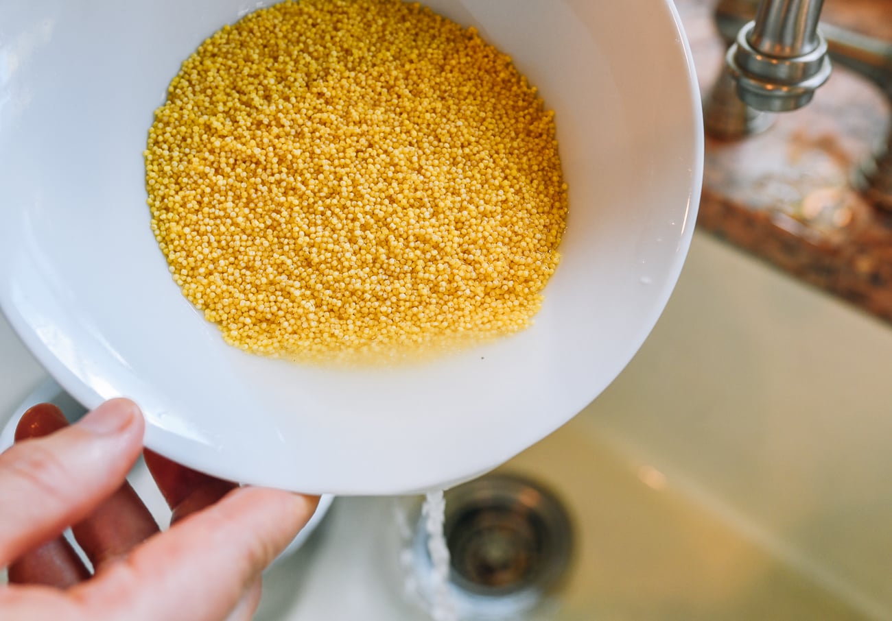 draining water from bowl of rinsed millet
