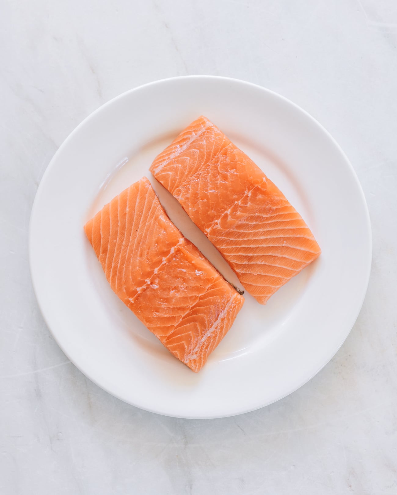 two raw salmon filets on white plate