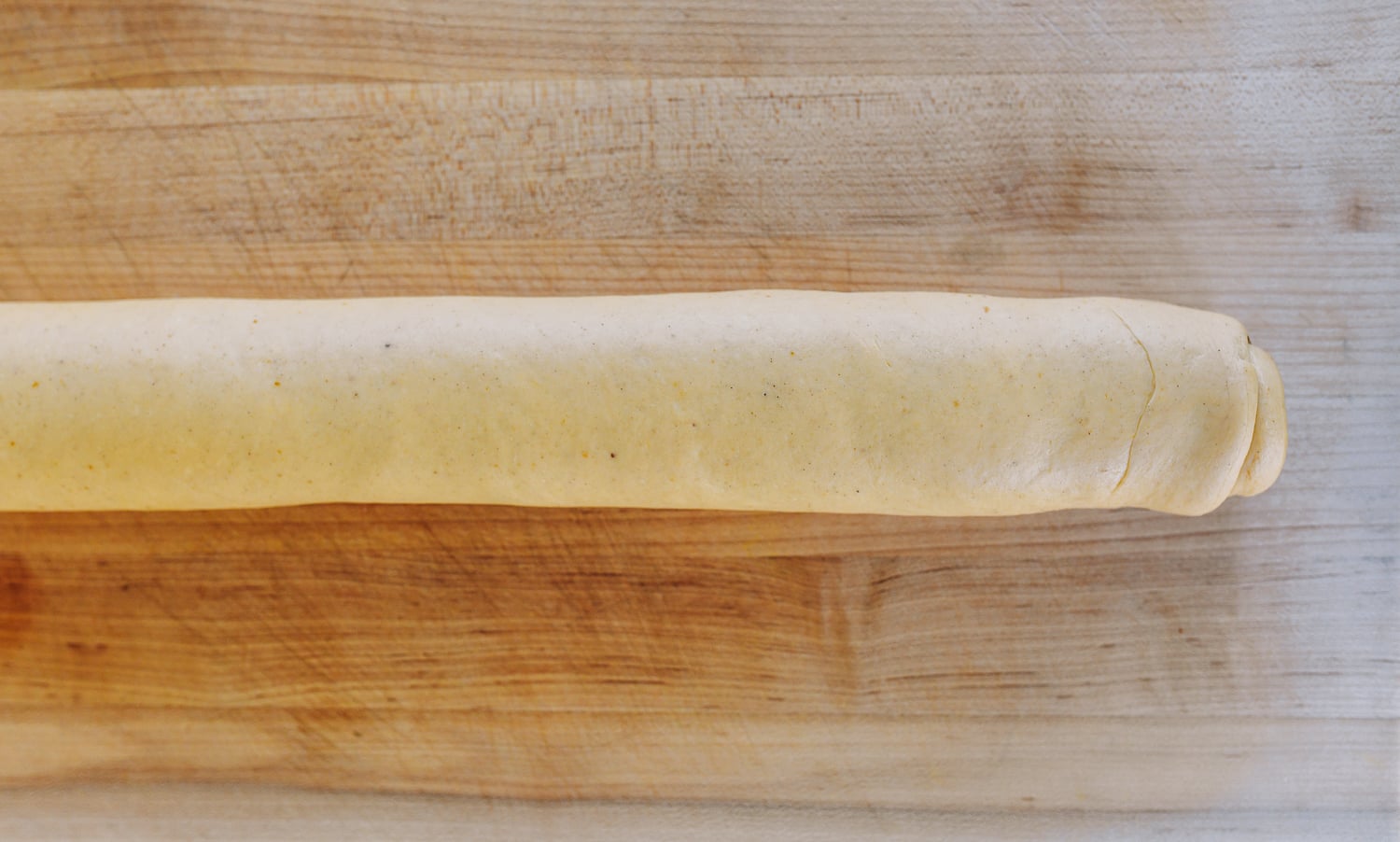 log of dough before cutting cinnamon rolls