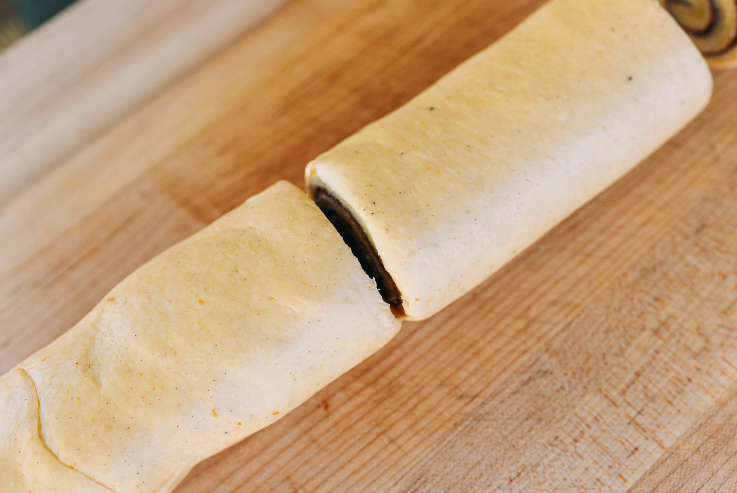 log of rolled cinnamon roll dough sliced in half